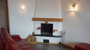 Ein Wohnzimmer mit Kamin, rotem Ledersofa und Fliesenboden.