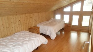 Ein Zimmer mit zwei Betten, Holzwänden und großen Fenstern.