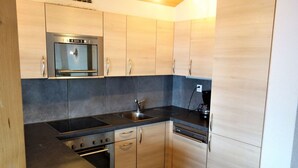 Eine moderne Küche mit Holzschränken, einem Edelstahlspülbecken, einem Einbauofen und einer Kaffeemaschine.