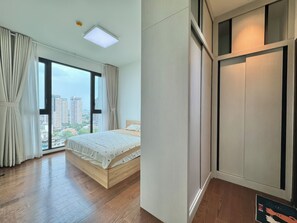 Ein Schlafzimmer mit großem Fenster, einem Bett und einem Kleiderschrank.