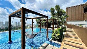 A rooftop pool with a hammock, wooden deck, and city views. - D'Edge Thao Dien (Ho Chi Minh City)