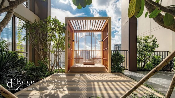 A modern outdoor seating area with a wooden structure and a view of the city skyline. - D'Edge Thao Dien (Ho Chi Minh City)