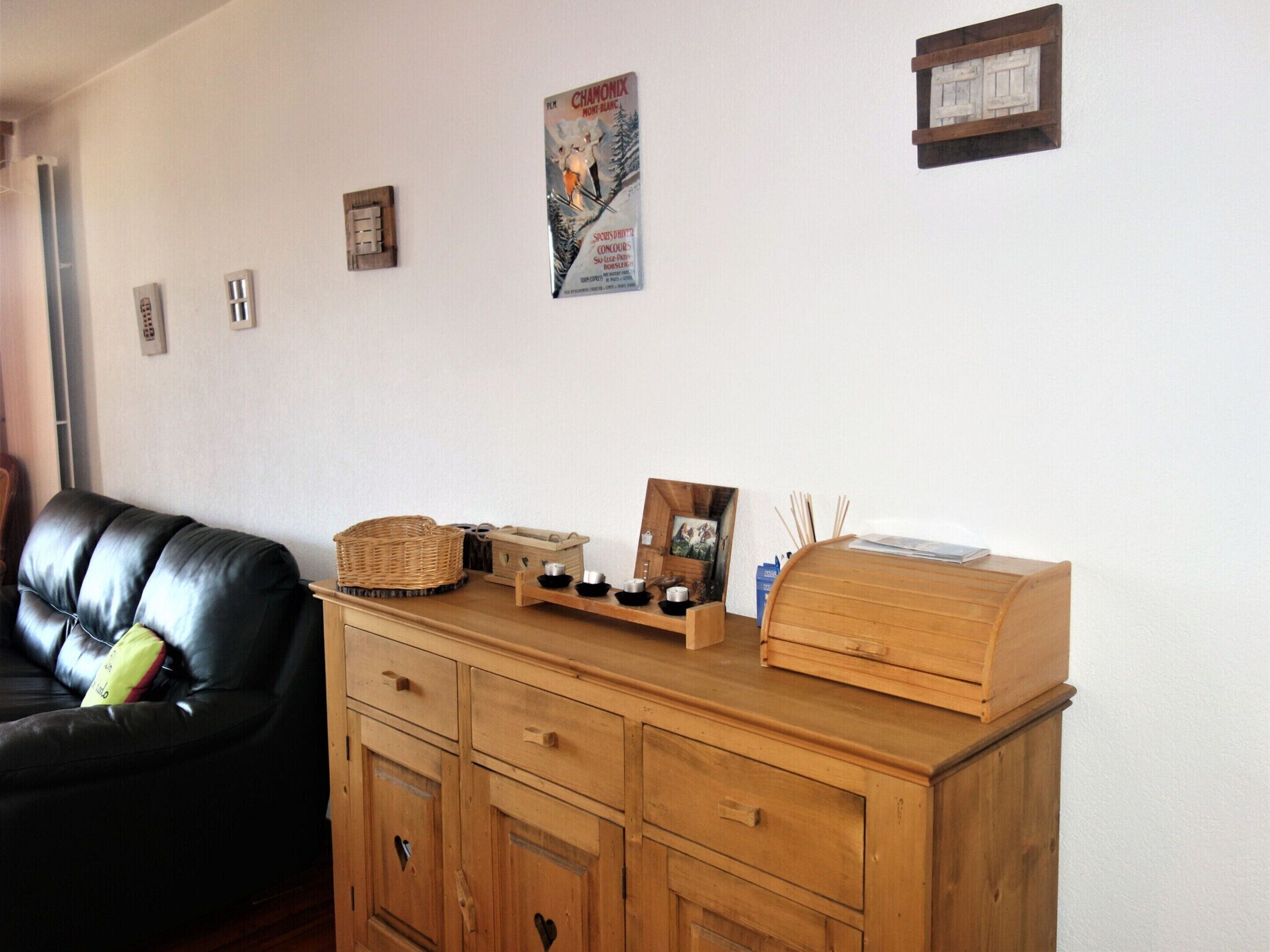 Un soggiorno con un mobile in legno, un divano in pelle nera e un quadro appeso al muro.