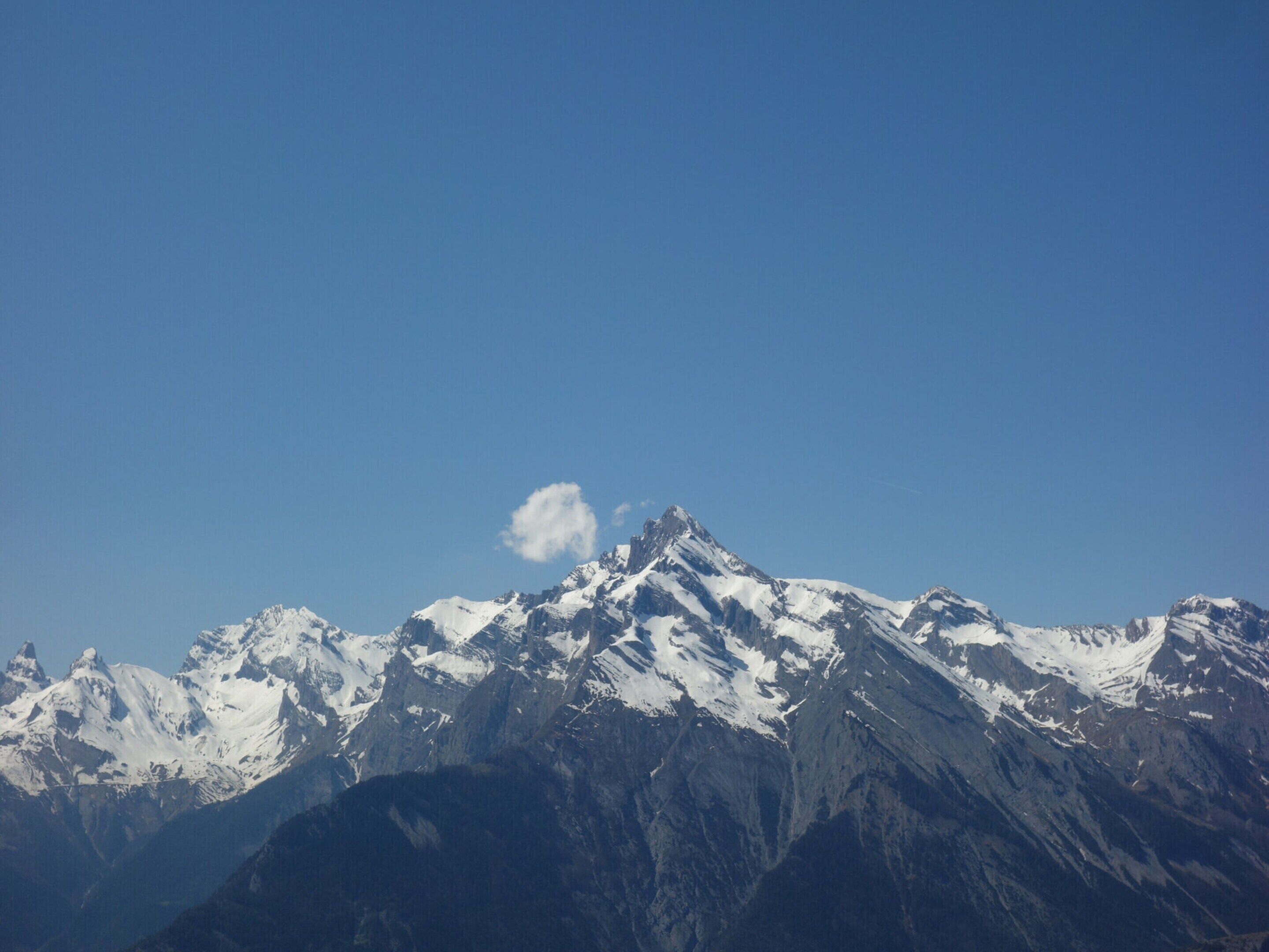 Une chaîne de montagnes dont les sommets enneigés se dressent sous un ciel bleu dégagé.