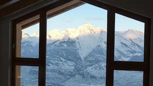 Een kamer met een groot raam dat uitzicht biedt op besneeuwde bergen.