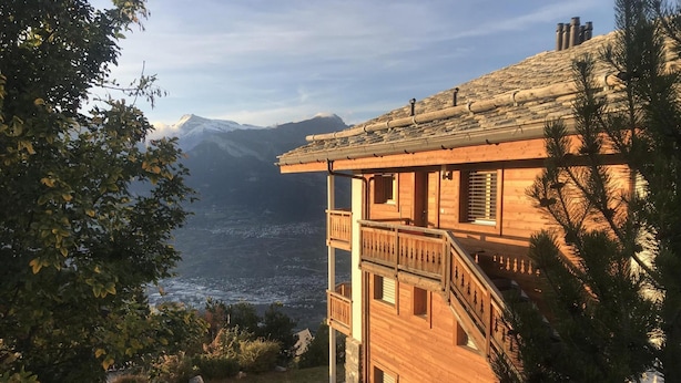 Een houten chalet met balkon en uitzicht op een bergachtig landschap.
