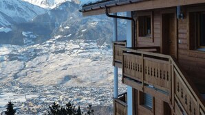 Een houten gebouw met balkon, uitkijkend op een besneeuwd berglandschap.