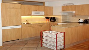 A compact kitchen with wooden cabinets, a microwave, a coffee maker, and a small sink. - Nice Apartment Near Ski-lift (Veysonnaz)
