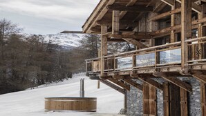 Een houten chalet met een balkon dat uitkijkt op een besneeuwd landschap.
