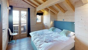 Een houten slaapkamer met een bed, een stoel en een raam.