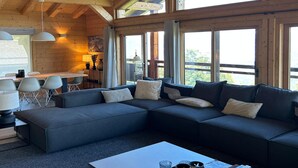 Een modern ingerichte cabin met een hoekbank, een eethoek en grote ramen.