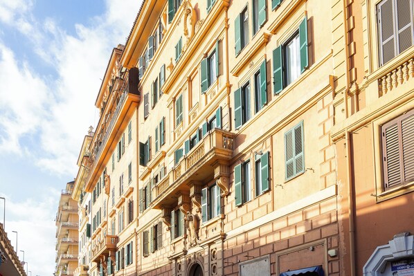 A multi-story building with balconies and green shutters.