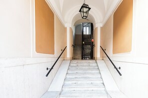 A staircase with marble steps and black handrails, leading to a door with a metal gate.