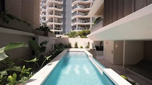 Ein Schwimmbecken, umgeben von Grünflächen und moderner Architektur.
