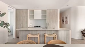 Eine moderne Küche mit einer zentralen Kochinsel, Holzschränken und einer Bar mit Barhocker-Platz.