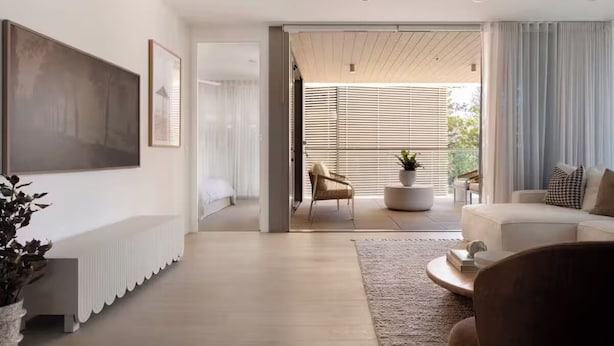 Ein modernes Wohnzimmer mit Sofa, Couchtisch und Fernseher. An der Wand befindet sich eine Bank und ein Blumentopf.
