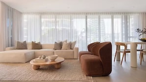 Ein modernes Wohnzimmer mit einem Ecksofa, einem runden Couchtisch und einem braunen Sessel.