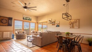 A spacious living room with a large sectional sofa, a dining table with chairs, and a ceiling fan.