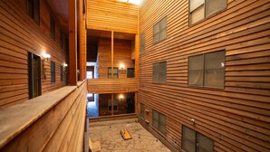 A wooden interior with a stone floor, wooden benches, and a staircase leading to an upper level.