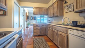 A kitchen with wooden cabinets, a dishwasher, and a window with a view.