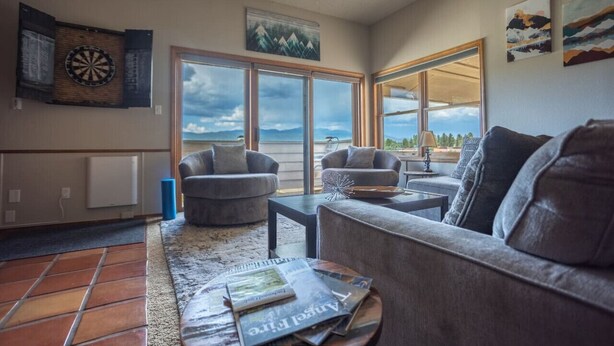A living room with a large window, a dartboard, and a view of the outdoors.