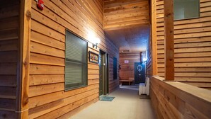 A wooden hallway with closed doors, a bench, and a fire extinguisher.