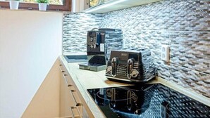 A kitchen with a modern stove, two coffee makers, and a tiled backsplash. - Comfortable Villa With Amenities (Harrachov)