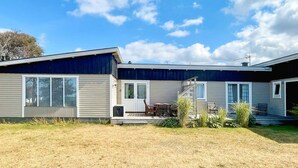 A two-story mobile home with a patio area, a small deck, and a covered outdoor seating area.