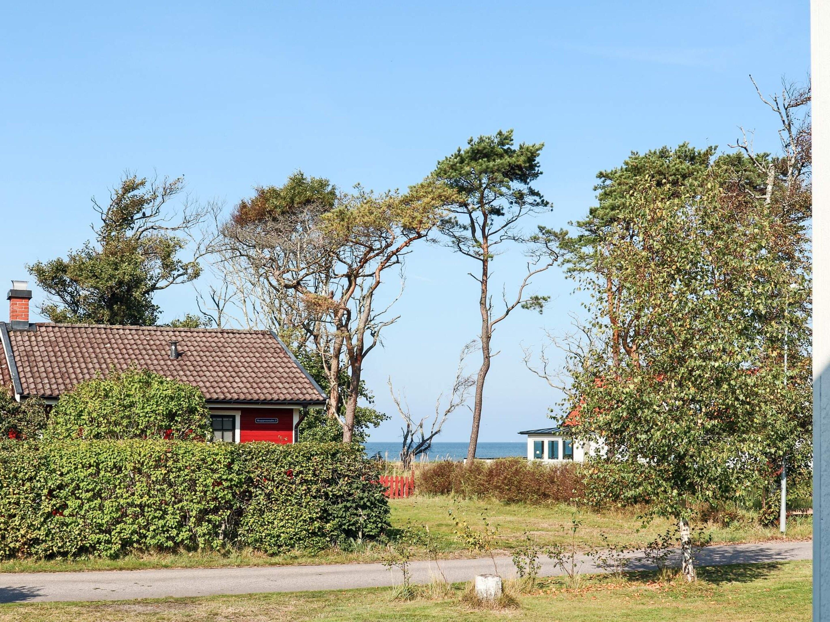 Une propriété située sur la côte, avec une maison rouge, un bâtiment blanc et une vue sur la mer.
