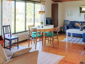 A room with a dining table, chairs, a sofa, and a television.