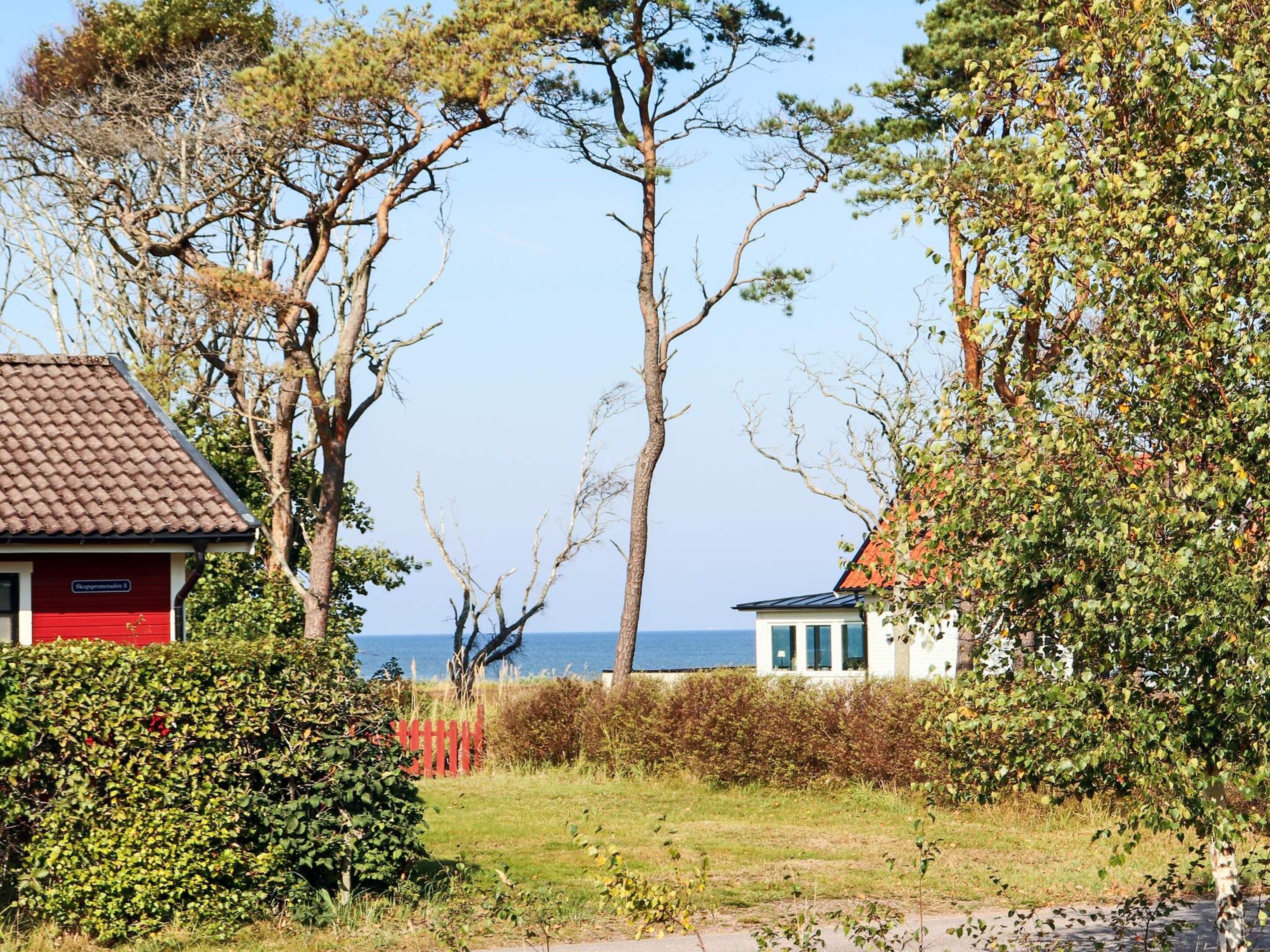 A coastal property with a red building, a white building with a red roof, and a view of the sea.