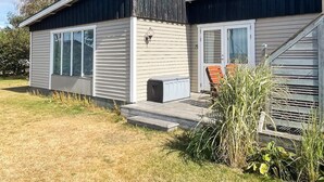 A two-story mobile home with a front porch, a small deck, and a window overlooking a grassy yard. - 6 Person Holiday Home in Skummeslovsstrand (Skummesloevsstrand)