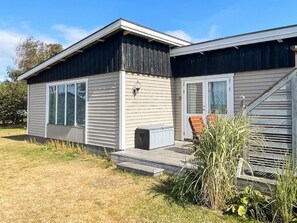 A two-story mobile home with a front porch, a small deck, and a window overlooking a grassy yard. - 6 Person Holiday Home in Skummeslovsstrand (Skummesloevsstrand)