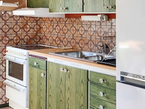 A kitchen with green cabinets, a stainless steel sink, and a white stove. - 6 Person Holiday Home in Skummeslovsstrand (Skummesloevsstrand)