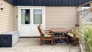 A covered patio with a wooden table and chairs, a bench, and a sliding glass door.