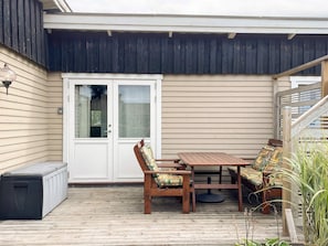 A covered patio with a wooden table and chairs, a bench, and a sliding glass door. - 6 Person Holiday Home in Skummeslovsstrand (Skummesloevsstrand)