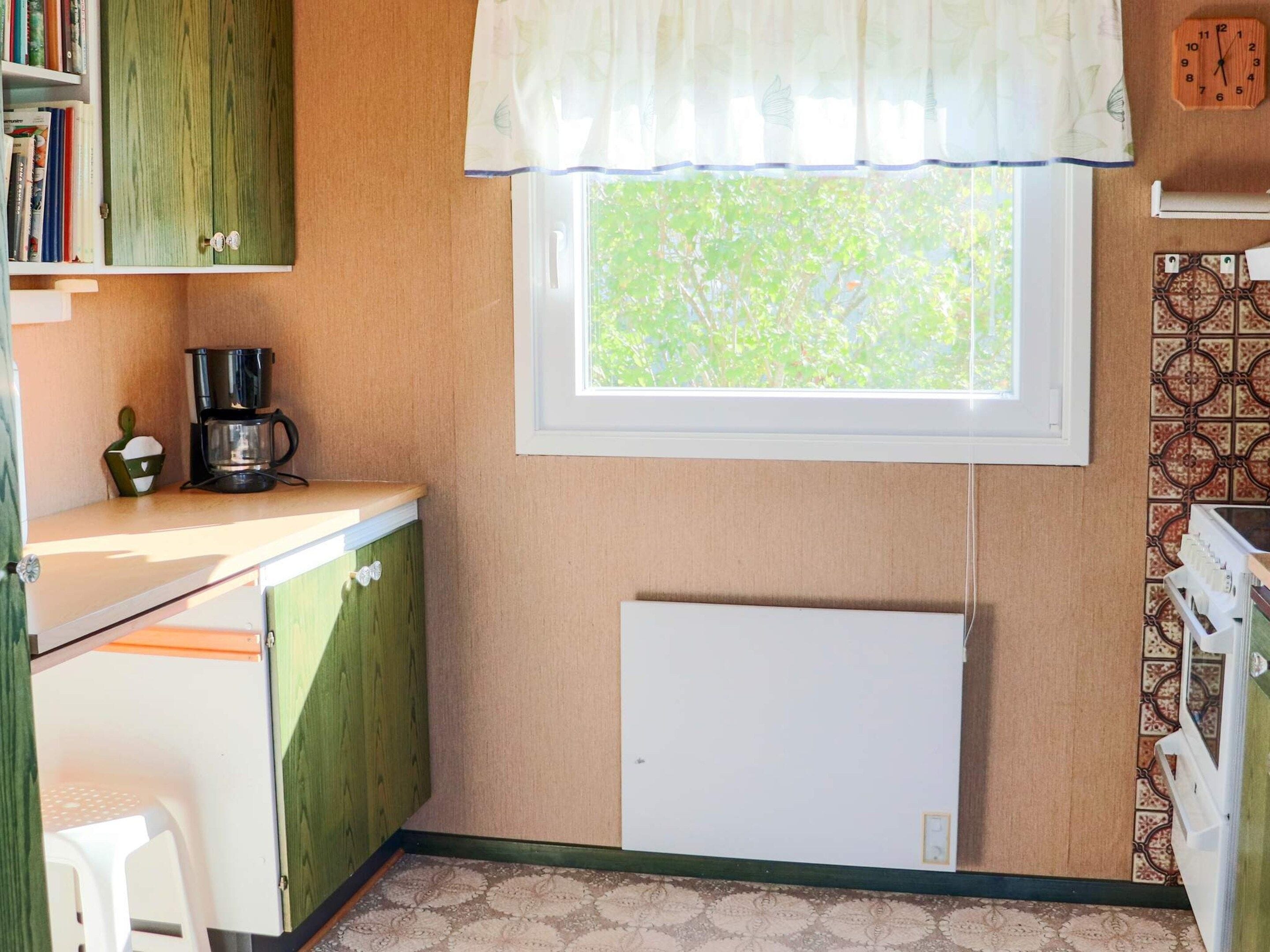 A compact kitchen with a window, a coffee maker, and a radiator.