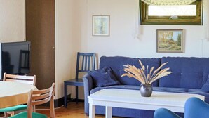A living room with a blue sofa, a white coffee table, and a TV on a stand. - 6 Person Holiday Home in Skummeslovsstrand (Skummesloevsstrand)
