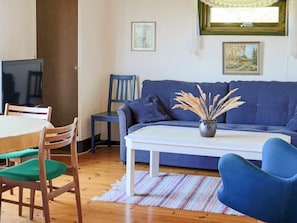 A living room with a blue sofa, a white coffee table, and a TV on a stand. - 6 Person Holiday Home in Skummeslovsstrand (Skummesloevsstrand)