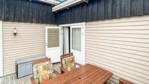 A patio with a wooden table and chairs, a radiator, and a door leading to an interior space.