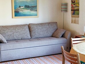 A room with a sofa, a table, a chair, a lamp, and a painting on the wall. - 6 Person Holiday Home in Skummeslovsstrand (Skummesloevsstrand)