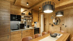 Una cocina moderna con armarios de madera, una mesa de comedor con sillas e iluminación colgante.