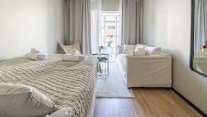 A hotel room with a bed, a sofa, a small table, and a mirror. - 4 Star Holiday Home in Solvesborg (Sölvesborg)