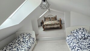 A bedroom with a sloped ceiling, a bed with patterned bedding, two bedside tables, and a hanging light fixture. - Charming family home with garden (Château-Gontier-sur-Mayenne)