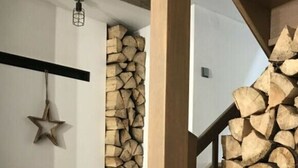 A cozy interior with a fireplace, wooden staircase, and a stack of firewood. - Holiday Villa for Families (Tanvald)