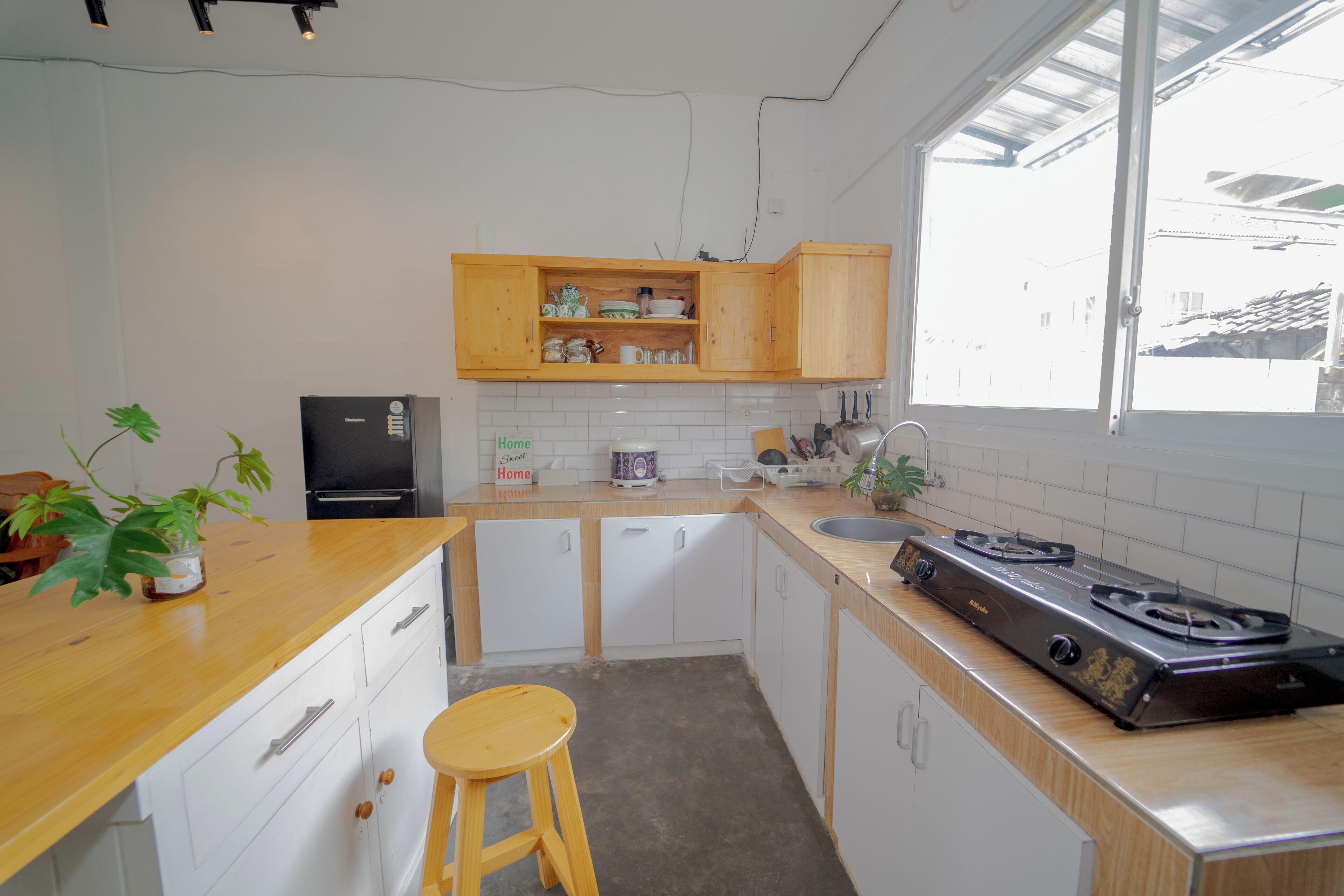 Una cucina con mobili in legno, un piano cottura in acciaio inossidabile, un lavello e un bancone con uno sgabello.