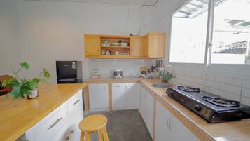 Una cucina con mobili in legno, un piano cottura in acciaio inossidabile, un lavello e un bancone con uno sgabello.