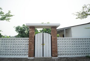 Una entrada cerrada con un portón blanco, pilares de ladrillo y una cerca blanca.