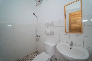 Un baño con inodoro, lavamanos, ducha y espejo con marco de madera.
