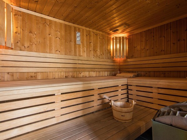 A wooden sauna with benches and a bucket. - Modern Apartment With Sauna (Veysonnaz)
